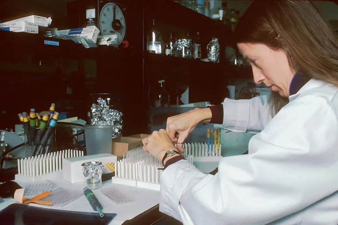 Researcher examining peptide molecules in laboratory with vials and molecular models for fat loss studies including AOD-9604 